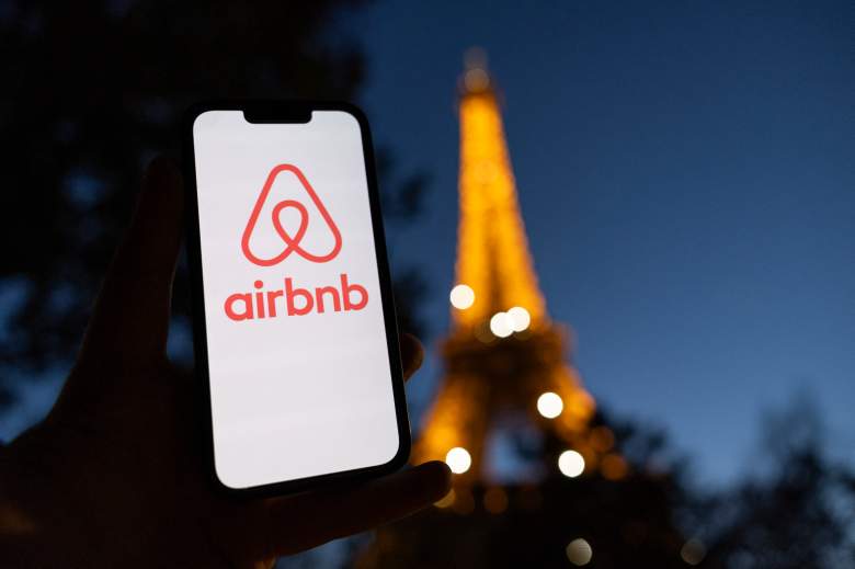 This photograph taken on October 28, 2024 shows the logo of short-term housing rentals online application Airbnb on a smart-phone screen in front of the Eiffel Tower in Paris. 